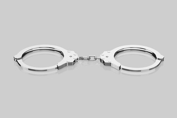 Isolated chrome Handcuffs on a Light Reflective Surface