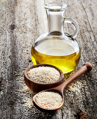 Sesame oil with seeds on wooden background