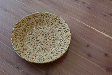 Decorative birch bark bowl, cut and stamped design, on wood background, copy space, horizontal aspect