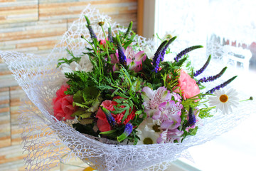 Bouquet of blue flowers of muscari, chamomiles, pink carnations, orchids and green leaves