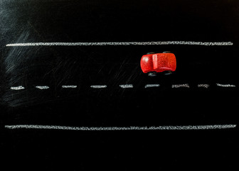 Red wooden car toy on the road of chalk board