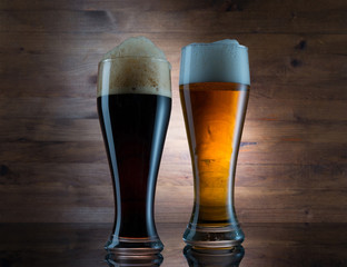 Two glasses of different colored beer on wooden background
