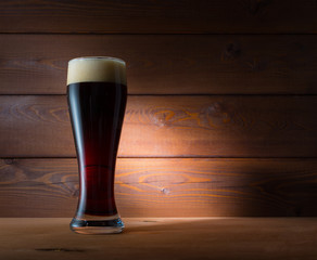 Glass of dark beer on wooden background