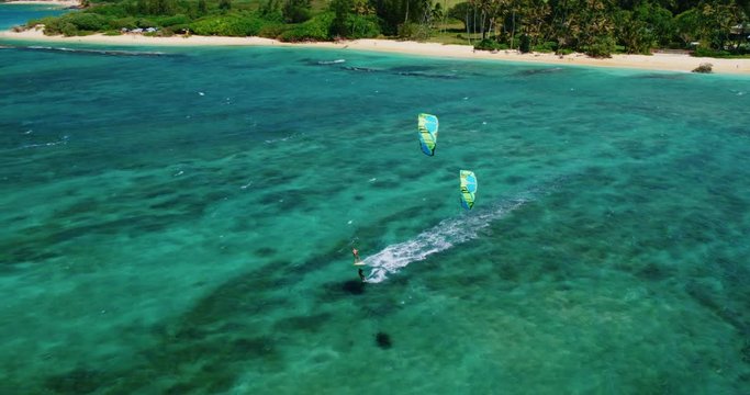 Cinematic aerial view of kitesurfers riding across the ocean