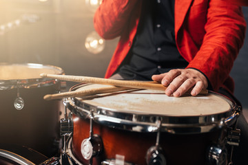 Fototapeta na wymiar Male drummer in red suit sitting behind drum set