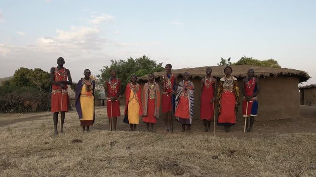 wide view of a group of maasai women and men singing at a village in kenya