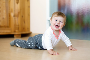 Naklejka premium Little smiling happy cute baby girl learning to crawl.