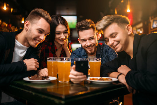 Fun company watches photo on phone in a sport bar