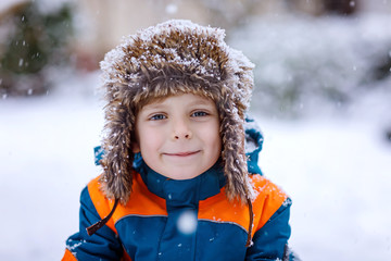 Happy kid boy having fun with snow in winter