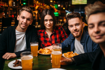 Friends sitting at the table with beer and crisps
