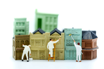 Miniature people : workman paint a toy house.