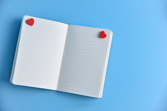 Two Red hearts with open blank pages of notebook.