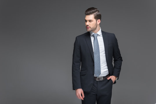 handsome bearded businessman in black suit, isolated on grey