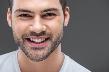 Obraz premium portrait of handsome smiling man looking at camera, isolated on grey