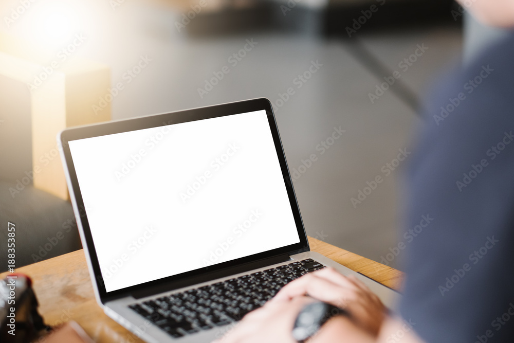 Wall mural mockup image of business man using and typing on laptop with blank white screen and coffee cup on gl