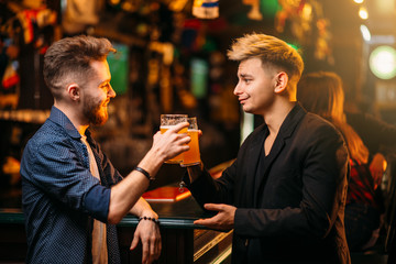 Men raised their glasses with beer in a sport pub