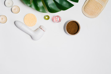 on the white table is an electric brush for cleaning the skin of the face, coffee scrub and sponge