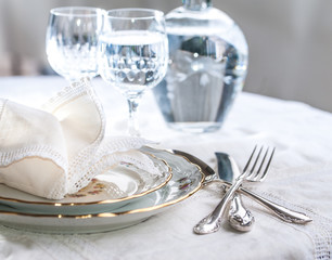 Luxury dinner set with silverware, elegant porcelain dishes, crystal glassware and vintage lace napkins