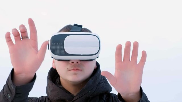 young man getting experience in using VR-headset outdoor at winter park,