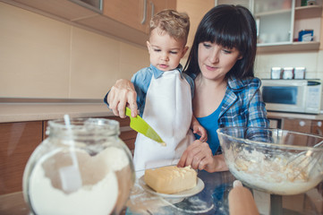 mother helping son cut butter with plastic knife