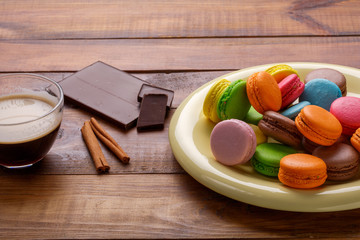 Coffee cup, cinnamon, chocolate and macaroons on old kitchen table.