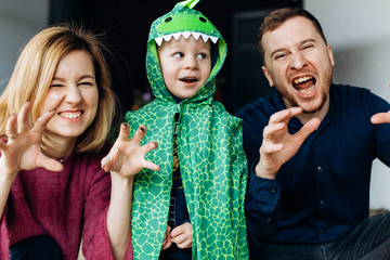 Parents and son in dragon cape look funny posing in the room