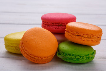A french sweet delicacy, macaroons variety closeup. White wooden background