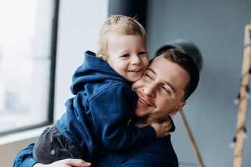 Father plays with little son in a cosy bright room