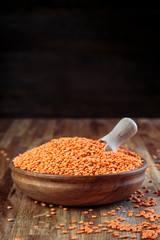 lentils red in a wooden bowl standing on the kitchen table made of oak