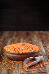 lentils red in a wooden bowl standing on the kitchen table made of oak
