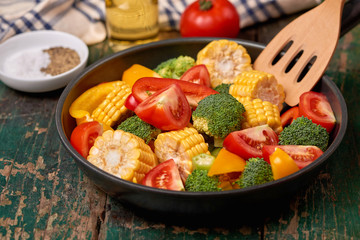 Fresh fruits and vegetables on a frying pan on an old wood background