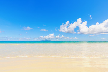 White sand tropical beach with far view of island and blue sky