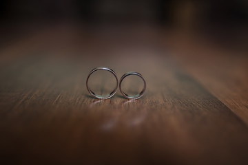 Beautiful wedding rings lie on a wooden surface