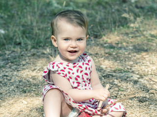 Baby girl is sitting on the ground.