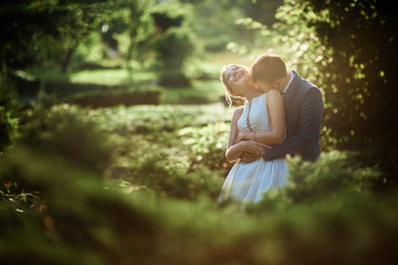 Bride and groom look gorgeous walking in a green summer park