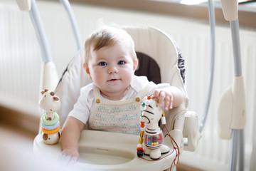 Cute adorable newborn baby girl sitting in swing indoors