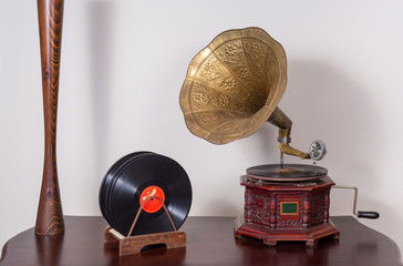 Still life of a  nineteenth century phonograph (gramophone) and vinyl records on a wooden table and...