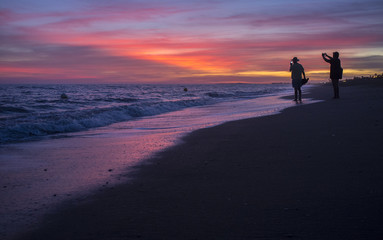 Fototapeta na wymiar Elder tourist couple taking pictures at Islantilla beach during the magnificent sunrise