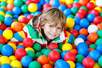Fototapeta na wymiar Little kid boy playing at colorful plastic balls playground
