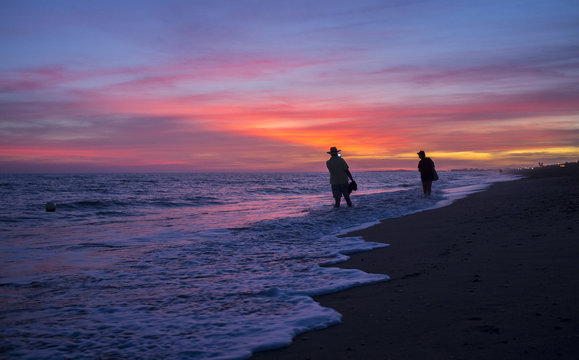 Elder tourist couple taking pictures at Islantilla beach during the magnificent sunrise