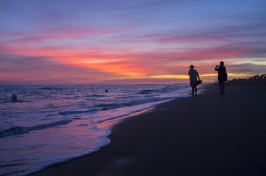 Elder tourist couple taking pictures at Islantilla beach during the magnificent sunrise