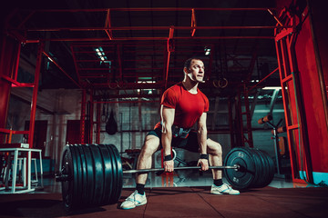 Muscular fitness man doing deadlift a barbell in modern fitness center. Functional training. Snatch...