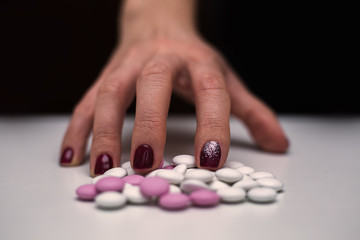 Closeup young woman hand with pills. Overdose and suicide concept.