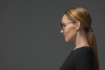 profile portrait of beautiful kazakh woman in eyeglasses looking away isolated on grey
