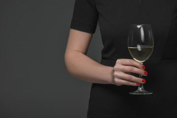 close-up partial view of woman in black dress holding glass of wine isolated on grey