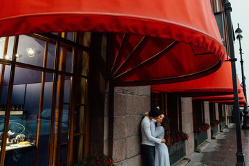 A loving couple hugs under the red store canopy on the street. Embrace.