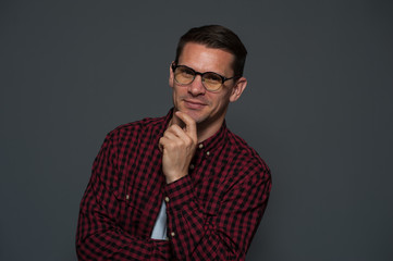 Obraz premium Portrait of successful young businessman with glasses smiling and looking at the camera on gray background