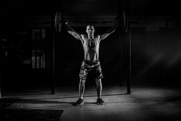 Fototapeta na wymiar Strong man lifting a barbell in the gym. Black and white photo