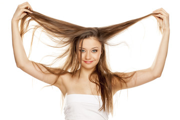 Obraz premium young blonde showing her long straight hair on white bckground