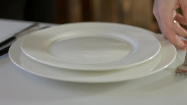 The waiter neatly laid out cutlery on a table with white tablecloth for banquet
